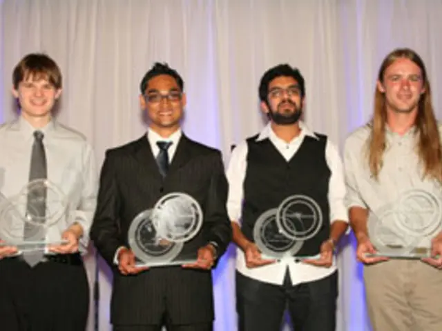 In this image there are four people standing with a smile on their face are holding trophies in...