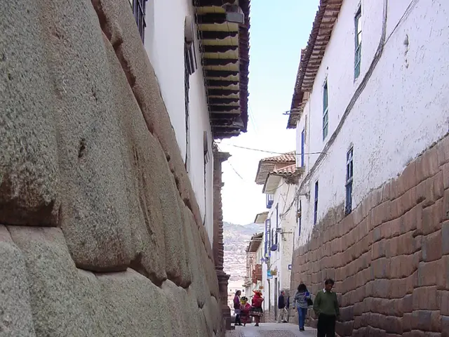 In this image I can see the street, few persons standing in the street and few buildings on both...